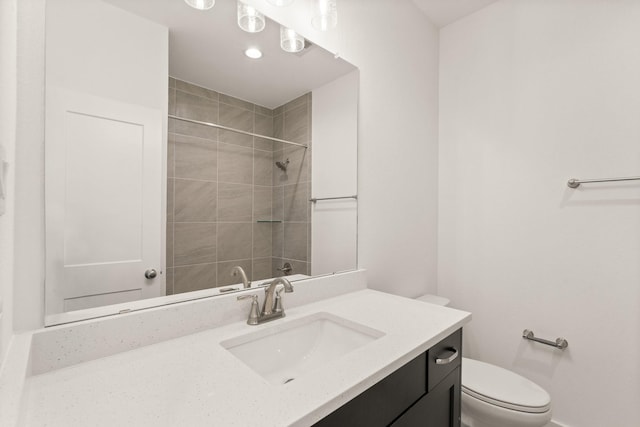 bathroom with tiled shower, vanity, and toilet