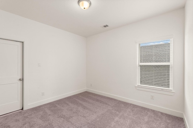 spare room with visible vents, light carpet, and baseboards