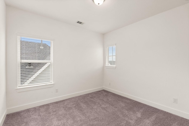 carpeted spare room featuring baseboards and visible vents