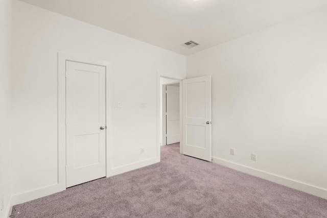 unfurnished bedroom with light colored carpet, visible vents, and baseboards