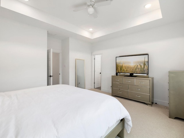 bedroom featuring light colored carpet, ceiling fan, and a raised ceiling