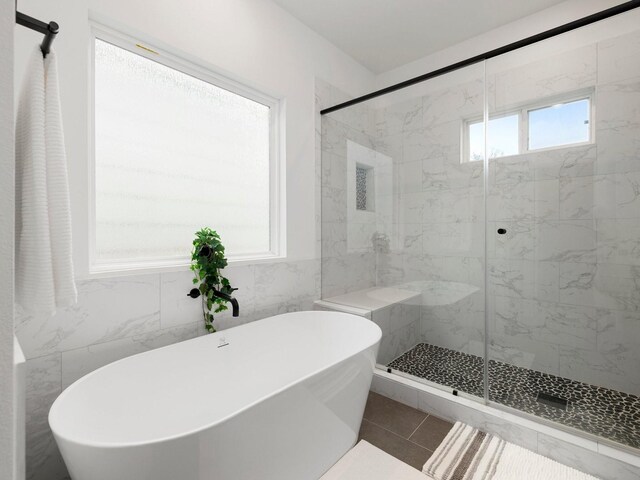 bathroom with tile walls, a shower with door, and tile patterned floors