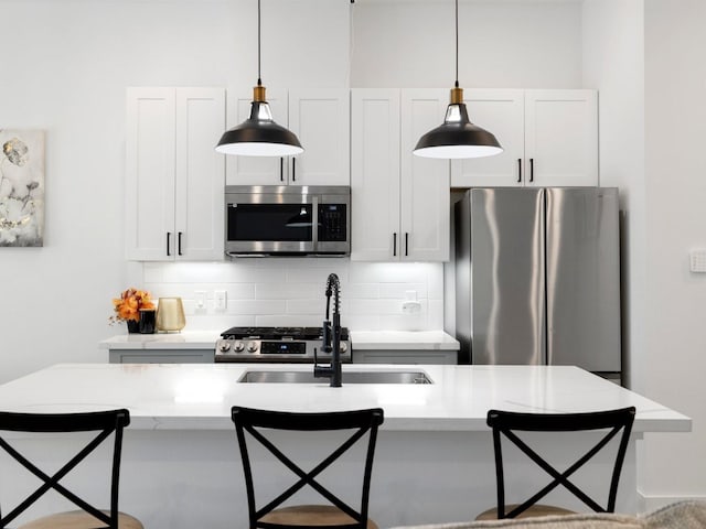 kitchen with a breakfast bar area, stainless steel appliances, decorative light fixtures, and decorative backsplash