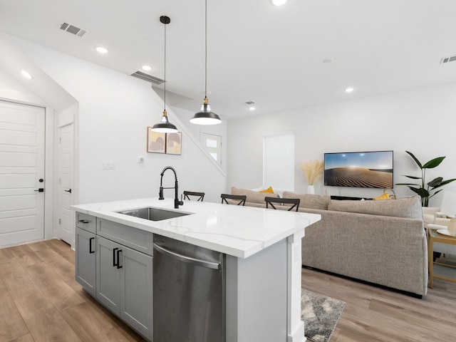 kitchen featuring an island with sink, gray cabinets, sink, stainless steel dishwasher, and light hardwood / wood-style floors