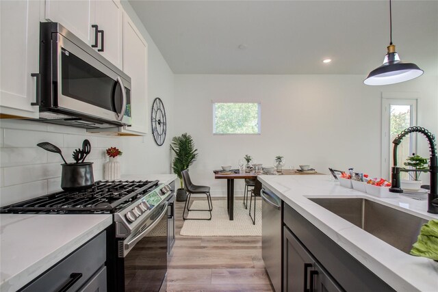 kitchen featuring light hardwood / wood-style flooring, decorative backsplash, stainless steel appliances, and white cabinets