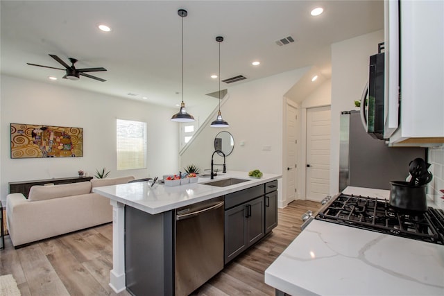 kitchen featuring appliances with stainless steel finishes, sink, light hardwood / wood-style flooring, and a kitchen island with sink