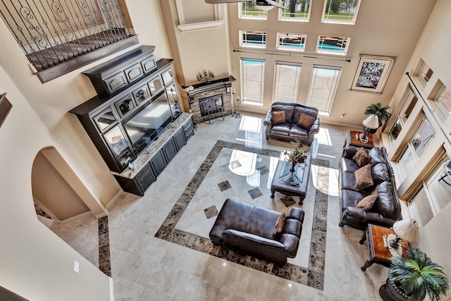 living room featuring light tile patterned floors, a wealth of natural light, a fireplace, and a towering ceiling