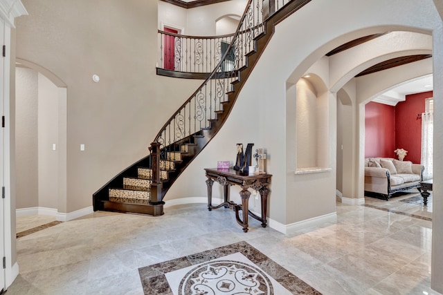 interior space featuring a towering ceiling, tile patterned floors, and crown molding