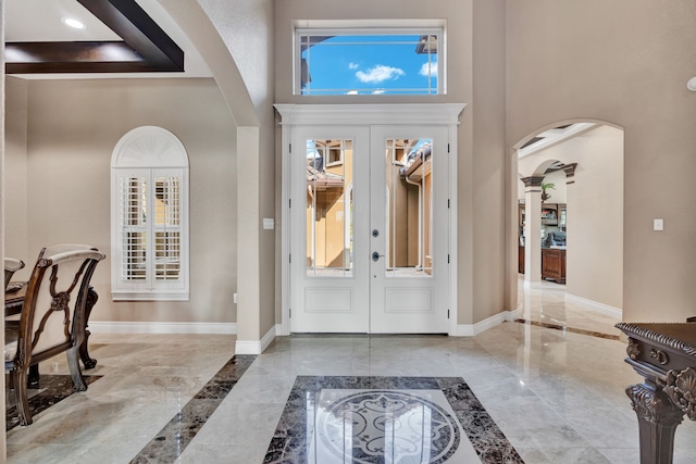 foyer featuring light tile patterned floors, french doors, a high ceiling, and a healthy amount of sunlight