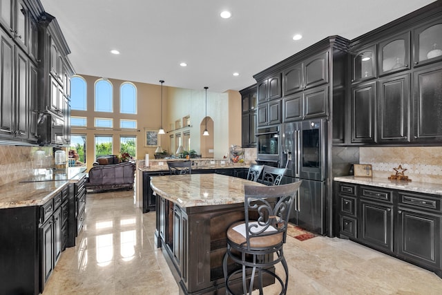 kitchen featuring tasteful backsplash, pendant lighting, light tile patterned floors, and light stone countertops