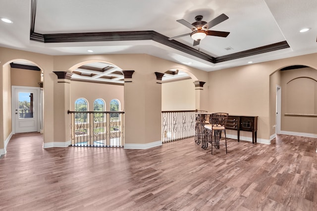 interior space with ceiling fan, coffered ceiling, wood-type flooring, and a raised ceiling