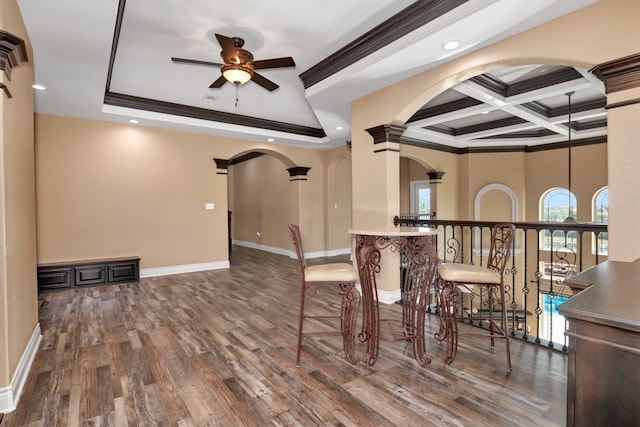 unfurnished dining area with coffered ceiling, dark hardwood / wood-style floors, ceiling fan, ornamental molding, and beamed ceiling