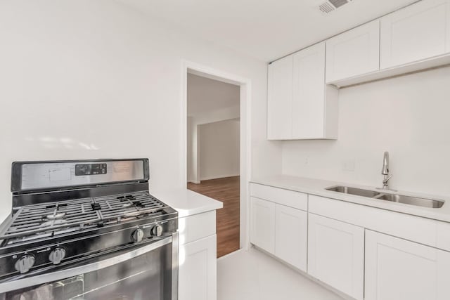 kitchen featuring sink, stainless steel range with gas stovetop, white cabinetry, and light hardwood / wood-style floors