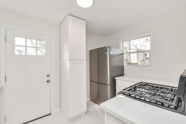 kitchen with light tile patterned floors, white cabinets, and stainless steel fridge