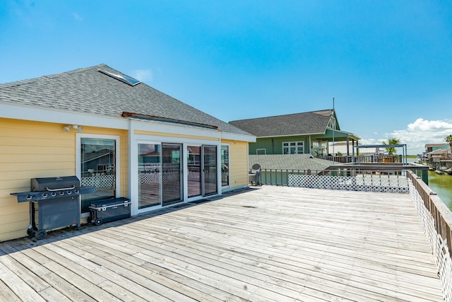 wooden terrace featuring a water view and a grill