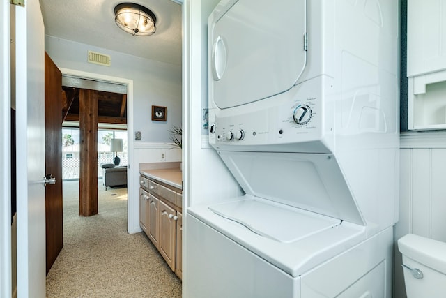 washroom featuring stacked washer and dryer and light colored carpet