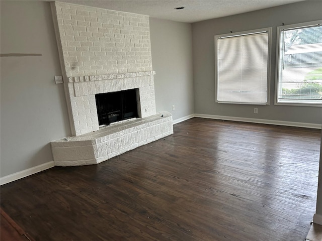 unfurnished living room with a textured ceiling, dark hardwood / wood-style flooring, and a fireplace