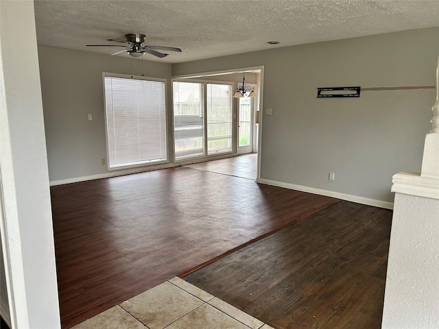 empty room featuring a textured ceiling, hardwood / wood-style floors, and ceiling fan with notable chandelier