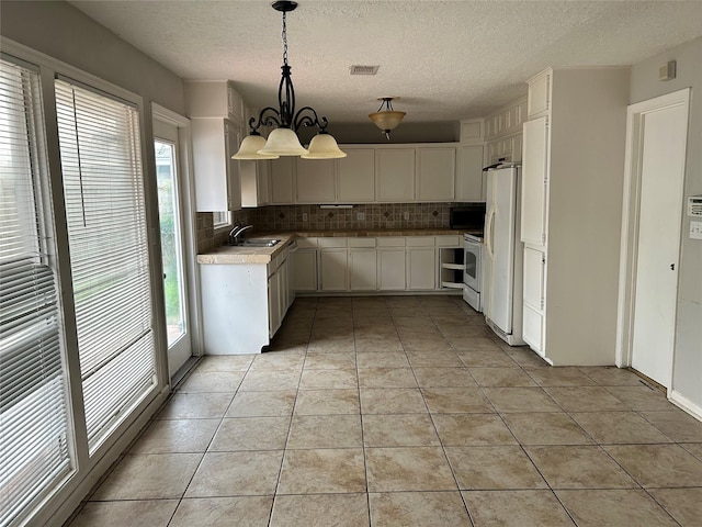 kitchen featuring white appliances, hanging light fixtures, light tile patterned floors, and tasteful backsplash