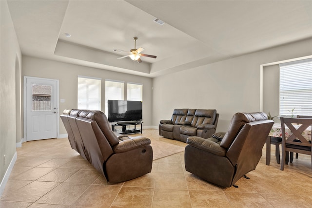 living room featuring a tray ceiling and light tile patterned floors