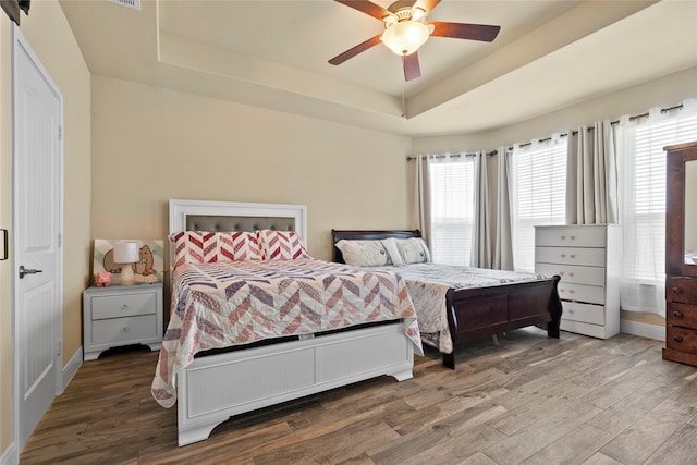 bedroom featuring ceiling fan, a raised ceiling, and hardwood / wood-style flooring