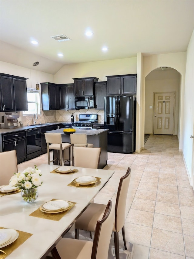 tiled dining space featuring sink and vaulted ceiling