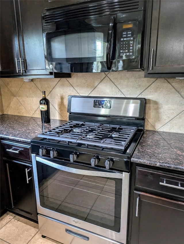 kitchen featuring stainless steel range with gas cooktop, light tile patterned floors, tasteful backsplash, dark stone counters, and dark brown cabinetry