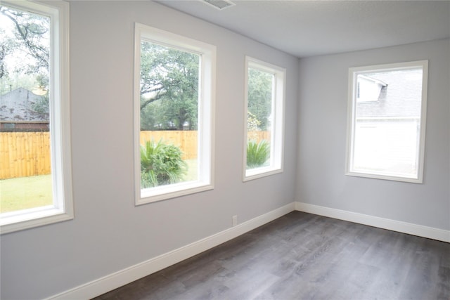 spare room with dark hardwood / wood-style flooring and a healthy amount of sunlight