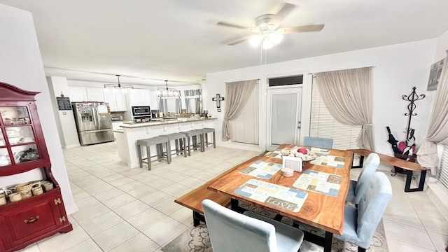 tiled dining space featuring ceiling fan with notable chandelier