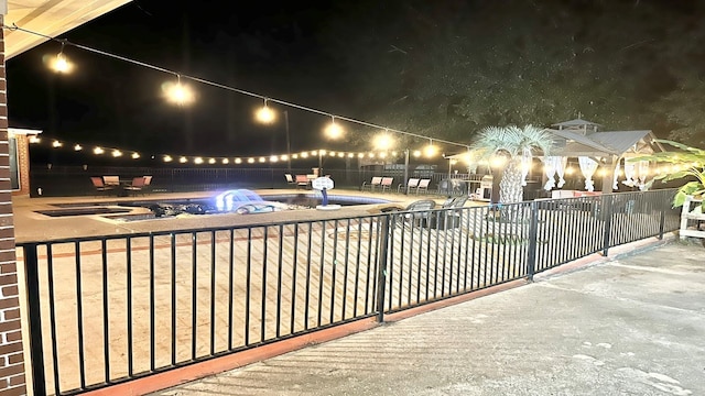 patio at night with a fenced in pool