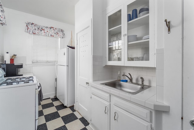 kitchen with white cabinets, light tile patterned floors, backsplash, white appliances, and sink