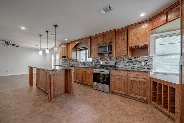 kitchen with pendant lighting, a center island, stainless steel appliances, decorative backsplash, and ceiling fan