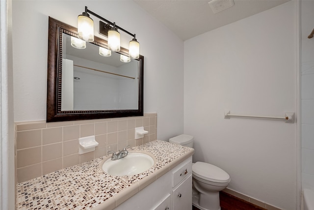 bathroom with vanity, toilet, backsplash, and a shower