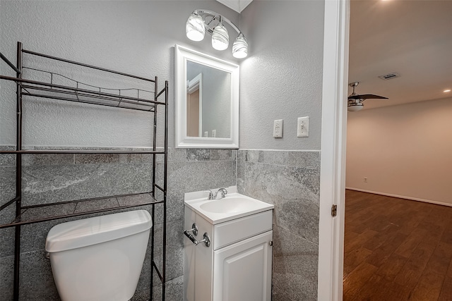 bathroom featuring vanity, toilet, hardwood / wood-style flooring, and tile walls