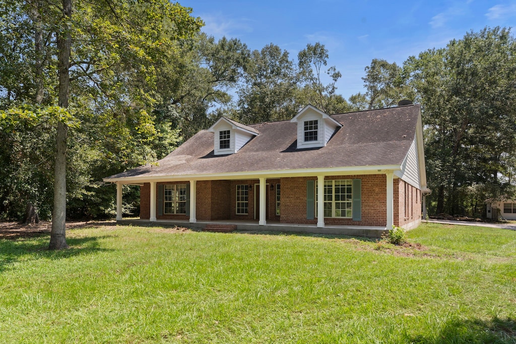 view of front of house with a porch, a front lawn, and brick siding