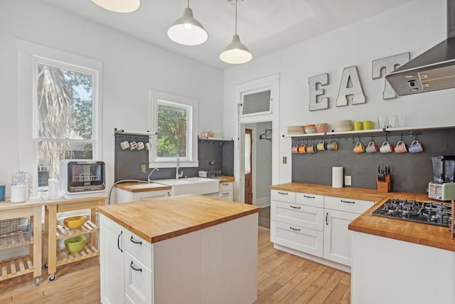 kitchen featuring light wood-style flooring, white cabinetry, open shelves, wooden counters, and black gas stovetop