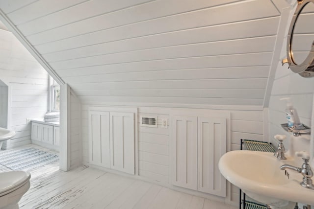 bathroom featuring lofted ceiling, toilet, a sink, and wood finished floors