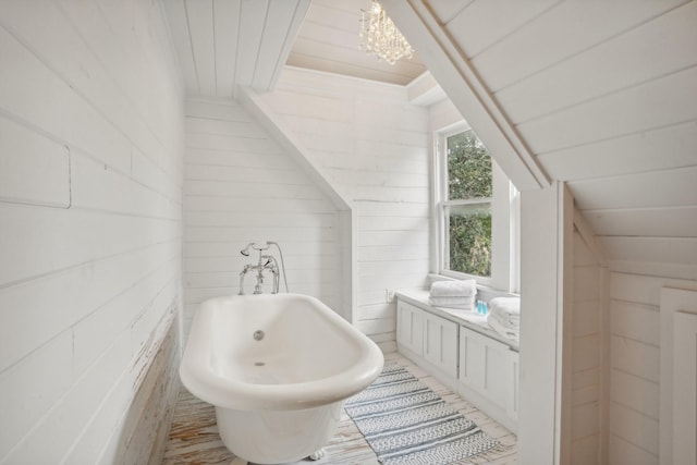 bathroom with wood ceiling, a soaking tub, wooden walls, and an inviting chandelier