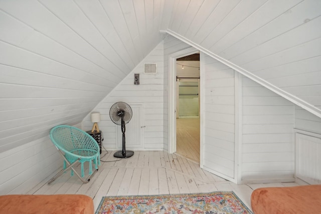 additional living space with wooden ceiling, wood walls, wood-type flooring, and lofted ceiling