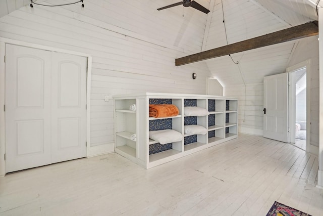 interior space featuring lofted ceiling with beams, wood walls, wood finished floors, and a ceiling fan