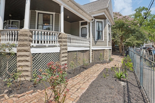 view of property exterior with fence, a porch, and roof with shingles