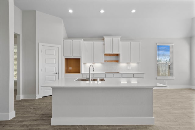 kitchen featuring white cabinets, sink, a kitchen island with sink, and lofted ceiling