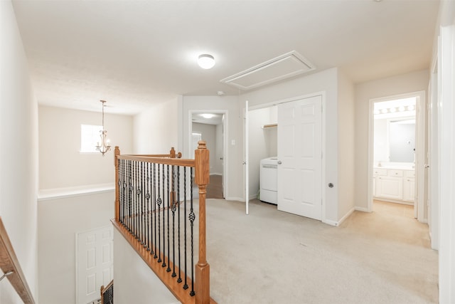 hallway with washer / dryer, a chandelier, and light colored carpet