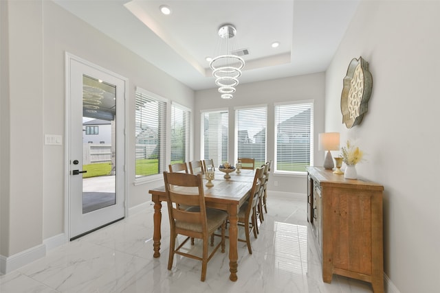 dining area featuring a notable chandelier, light tile patterned flooring, and a raised ceiling