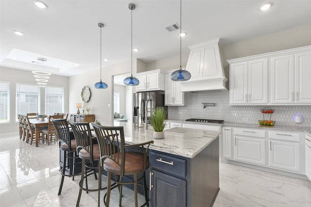 kitchen featuring hanging light fixtures, backsplash, white cabinetry, custom exhaust hood, and light tile patterned floors