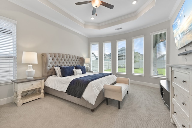 bedroom with ceiling fan, crown molding, light carpet, and a tray ceiling