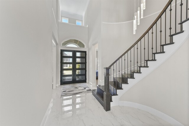 entrance foyer with a towering ceiling, french doors, and tile patterned floors