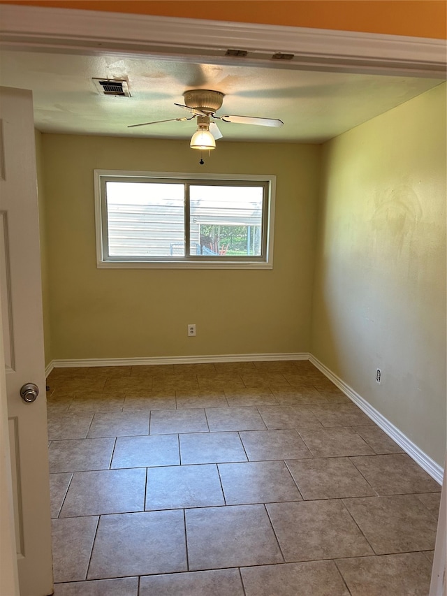 tiled spare room featuring ceiling fan