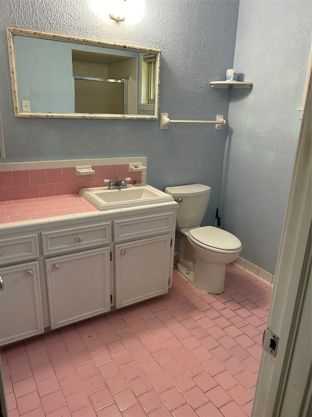 bathroom with toilet, tile patterned floors, vanity, and decorative backsplash