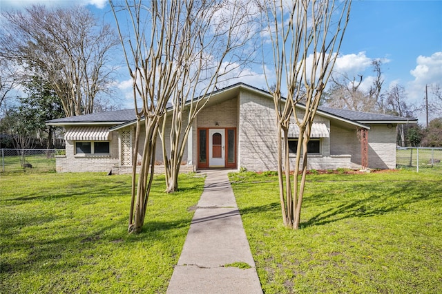 mid-century modern home featuring a front yard, brick siding, and fence